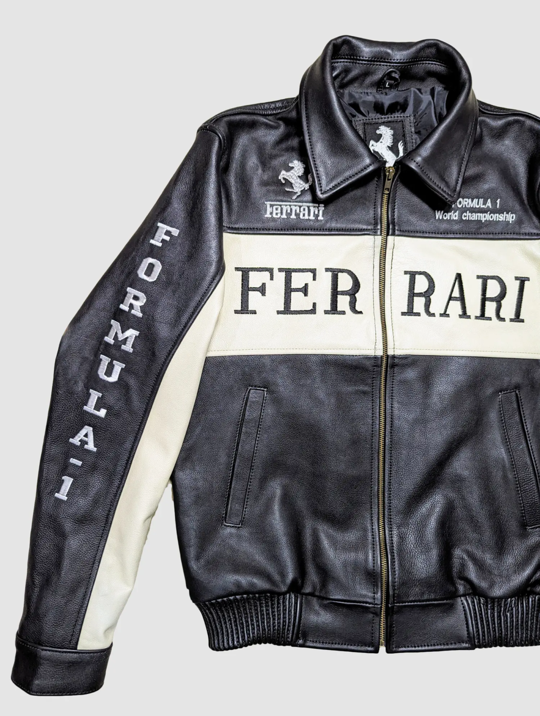 Front view of a black and off-white leather Ferrari Formula 1 World Championship jacket with "FERRARI" text on the chest.