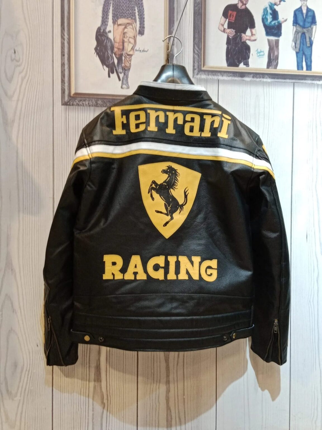 Full front view of a black leather Ferrari RACING jacket with bold yellow text, Bell Helmets, and Chesterfield sponsor patches.